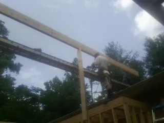 Carpenter setting a ridge beam over a new addition frame — Ice Dam Removal by Roofing Brothers in Rocky Mount